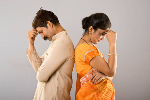 depressed indian couple standing back to back